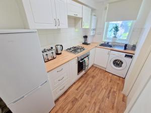 a kitchen with white cabinets and a washer and dryer at Flat in Battersea, 5 minutes from Clapham Junction Station in London