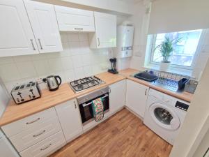 a kitchen with white cabinets and a washer and dryer at Flat in Battersea, 5 minutes from Clapham Junction Station in London