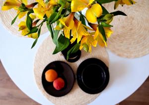 a vase filled with yellow flowers on a white plate at Baltic Breeze Studio Gdynia -stylowe studio 2-os, blisko morza in Gdynia +3 photos