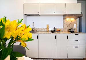 a kitchen with white cabinets and yellow flowers at Baltic Breeze Studio Gdynia -stylowe studio 2-os, blisko morza in Gdynia