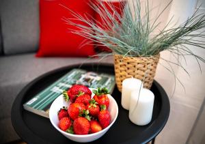 a table topped with two bowls of strawberries and a vase at Baltic Breeze Studio Gdynia -stylowe studio 2-os, blisko morza in Gdynia
