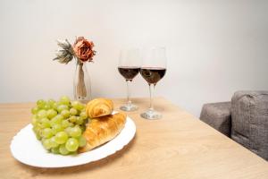 House 22A Studio Apartments في كاوناس: طاولة مع كأسين من النبيذ وصحن من الخبز والعنب