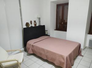 a bedroom with a bed and a chair and a window at T1 centre ville Aubenas in Aubenas