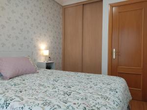 een slaapkamer met een bed en een houten deur bij Apartamento Gloria en Oviedo in Oviedo
