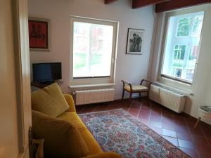 un soggiorno con un divano e due finestre di Ferienwohnung im historischen Zentrum 25562 a Weener