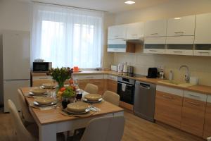 a kitchen with a wooden table with chairs and a dining room at Flower Apartman 4 