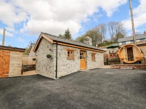 a stone house with a garage in a parking lot at The Old Cobblers Shop in Llandrindod Wells