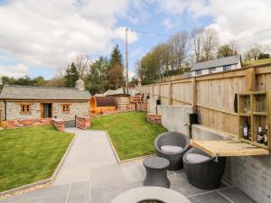 a backyard with a stone wall and a patio with stools at The Old Cobblers Shop in Llandrindod Wells