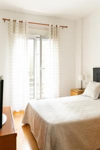 a white bedroom with a bed and a window at Apartamento riosella centro in Ribadesella