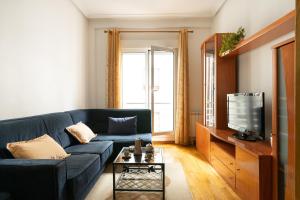 a living room with a blue couch and a tv at Apartamento riosella centro in Ribadesella