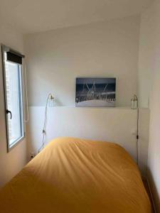 - une chambre avec un lit et une couverture jaune dans l'établissement Jolie maison de pêcheur ARAGO aux Sables d'Olonne, à Les Sables-dʼOlonne
