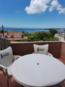 una mesa blanca y sillas en un balcón con vistas al océano en Apartamento en sanxenxo duplex, en Sanxenxo