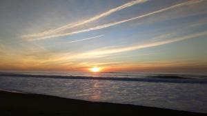 una puesta de sol en la playa con el océano en Joli T2 38 m2 rénové idéalement situé, en Seignosse