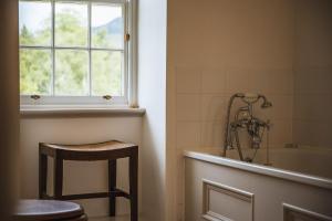a bathroom with a tub and a stool and a window at Coulin Farmhouse in Kinlochewe