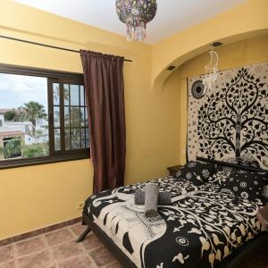 a bedroom with a black and white bed and a window at Los Amigos Hostel Tenerife in La Mareta