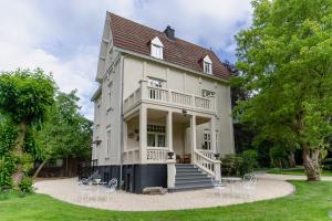 a large white house with chairs in front of it at Villa les Bruyères in Dilsen-Stokkem