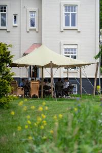 Un groupe de personnes assises sous un parapluie d'aigle dans l'herbe dans l'établissement Villa les Bruyères, à Dilsen-Stokkem