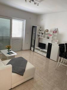 a living room with a white couch and a television at Apartments MaRo in Pag