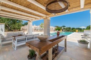 un patio al aire libre con una mesa de madera y una piscina en Borgo Altobello, en Cisternino