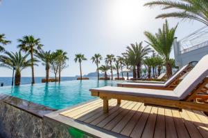 Una piscina de resort con un banco y palmeras. en ELYSIUM GARDEN HOTEL, en Bozyazı 17 fotos más