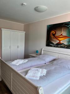 two beds in a bedroom with a painting on the wall at Kreatives Wohnen unter Reet ruhig und doch zentral in Schwabstedt