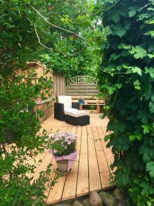 une terrasse en bois avec un banc et un pot de fleurs dans l'établissement Kreatives Wohnen unter Reet ruhig und doch zentral, à Schwabstedt 5 autres photos