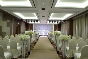 una fila de mesas y sillas en una habitación con flores blancas en Astar Hotel en Jeju