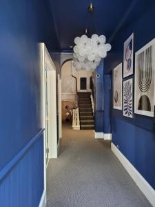 ein Flur mit blauen Wänden und einer Decke mit einem Kronleuchter in der Unterkunft Mentone Hotel in London