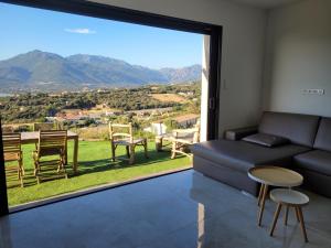 een woonkamer met een bank en een groot raam bij Appartement neuf 3 chambres vue mer Propriano in Propriano