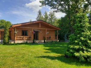 a log cabin in a yard with a green grass at Forest Edge Lodge in Riga