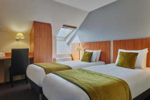 a hotel room with two beds and a desk at Kyriad Paris Sud Les Ulis Courtaboeuf in Les Ulis