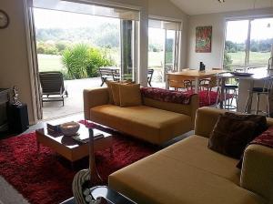 una sala de estar con 2 sofás y una ventana grande en Mistry Hideout - Lakes Resort Pauanui Home, en Pauanui