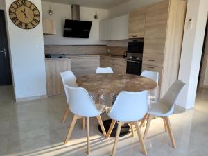 a kitchen with a glass table and white chairs at Appartement neuf 3 chambres vue mer Propriano in Propriano