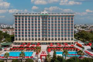 Megasaray Westbeach Antalya في أنطاليا: فندق ذو مبنى كبير به مسبح