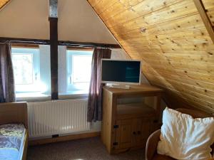 a room with a tv on a wooden table with two windows at Haus Mohnke in Hiddensee