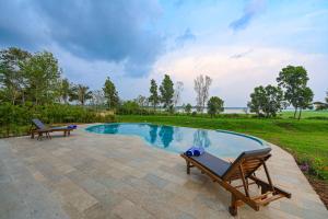 a swimming pool with two lounge chairs next to it at Fireflies Kabini in Begūr