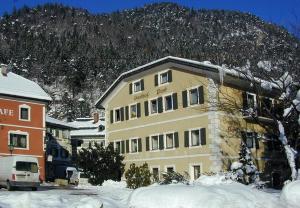 un edificio en la nieve frente a una montaña en Gasthof Post, en Oberdrauburg