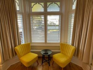 two yellow chairs and a table in front of a window at Beach Lodge in Bournemouth