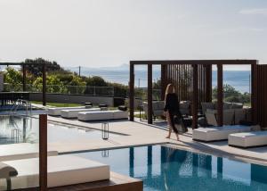 a woman walking by a swimming pool in a hotel at Borosso Villa, an Exclusive Resort, By ThinkVilla in Skaleta