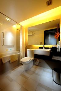 een badkamer met een toilet, een wastafel en een bad bij Grand Margherita Hotel in Kuching