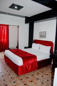 - une chambre avec un grand lit et une couverture rouge dans l'établissement Hotel Al Khaima, à Assilah