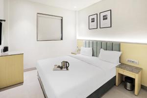 una camera da letto con un letto bianco con un microscopio di FabHotel Oasis Yellow Courtyard a Bhopal