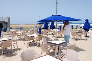 a person standing under an umbrella on a beach at Hotel Al Khaima in Asilah