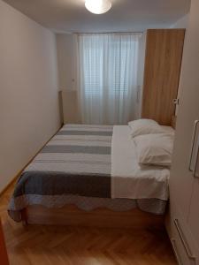 uma cama num pequeno quarto com uma janela em Apartments Mlacovic em Rab