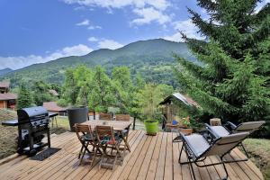 una terrazza in legno con tavolo, sedie e griglia di Studio du Coin - Vue montagne, au calme, Terrasse - AravisTour a Les Villards-sur-Thônes