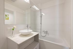 a white bathroom with a sink and a bath tub at Yourapartment Theresien in Vienna