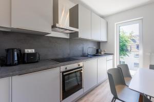 a kitchen with white cabinets and a sink and a stove at Glück Auf Appartements Schleiermacherstraße Duisburg in Duisburg
