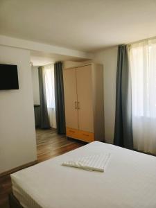 a bedroom with a bed and a dresser and curtains at Vila Eric in Eforie Sud