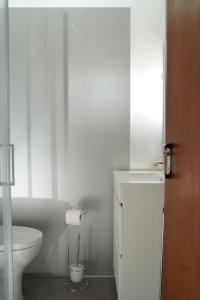 a white bathroom with a toilet and a sink at Casa Origens in Seia