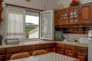 a kitchen with wooden cabinets and a large window at Casa Origens in Seia